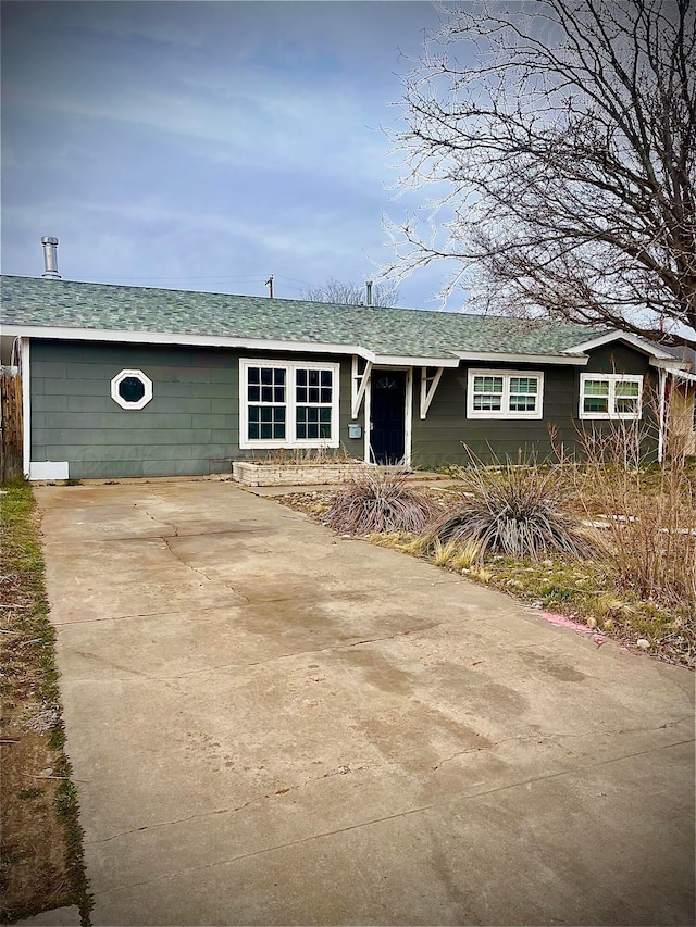 single story home with driveway and roof with shingles