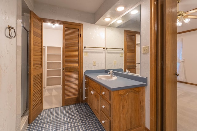 bathroom with ceiling fan, vanity, a shower with door, and tile patterned flooring