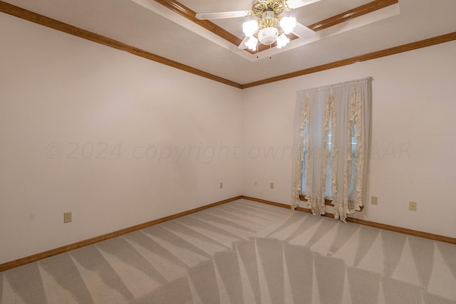 unfurnished room featuring ceiling fan, a raised ceiling, crown molding, and carpet