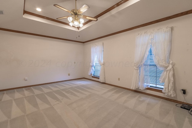 empty room featuring crown molding, light carpet, ceiling fan, and a raised ceiling