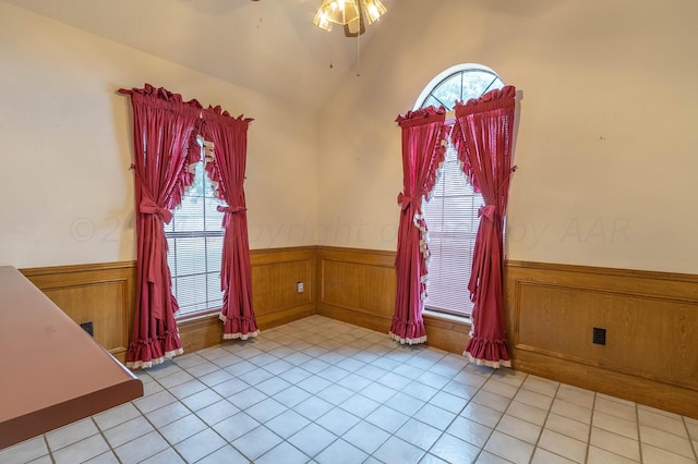 spare room featuring wooden walls, vaulted ceiling, light tile patterned floors, and ceiling fan