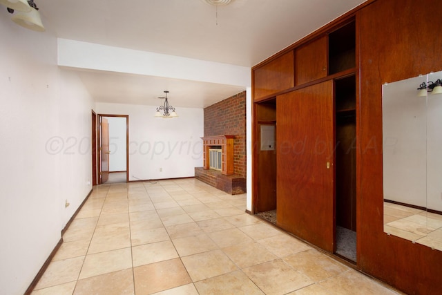 3115 Palm St, Amarillo, TX 79107 - empty room with a chandelier, light tile patterned flooring, and a brick fireplace