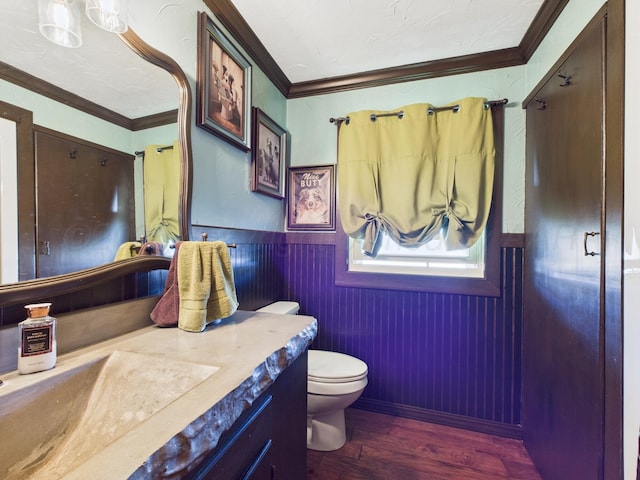 bathroom featuring a wainscoted wall, toilet, vanity, wood finished floors, and ornamental molding