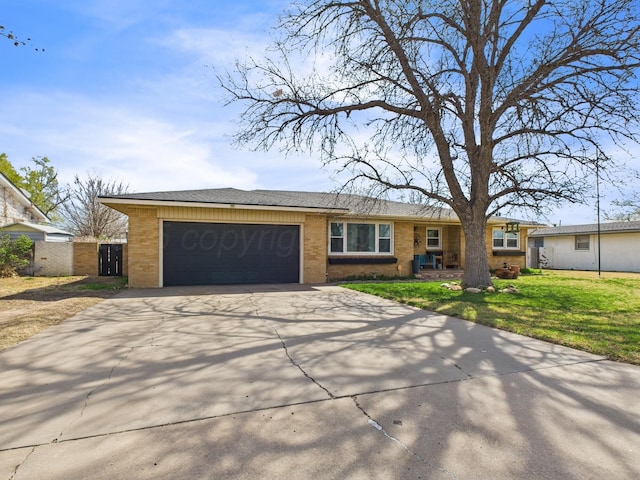 ranch-style home featuring concrete driveway, fence, an attached garage, a front lawn, and brick siding