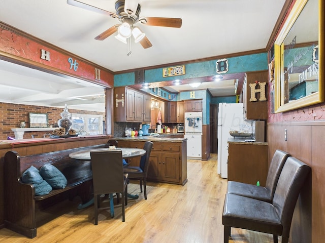 kitchen featuring a wainscoted wall, a ceiling fan, a peninsula, light wood-type flooring, and ornamental molding