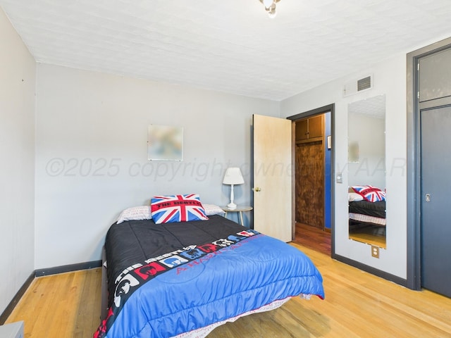 bedroom with baseboards, visible vents, and light wood-style flooring
