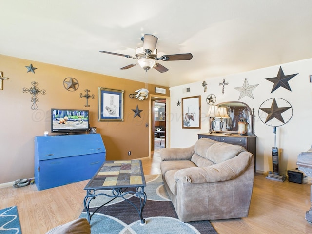 living room featuring baseboards, wood finished floors, and a ceiling fan