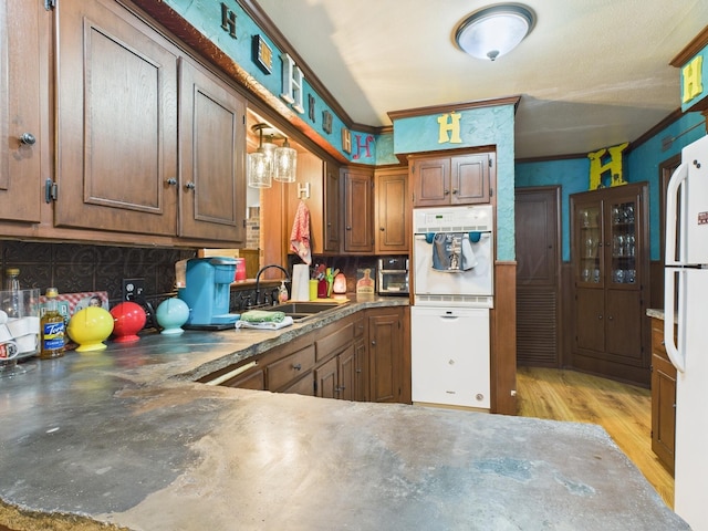 kitchen with crown molding, backsplash, a sink, light wood-style flooring, and white appliances