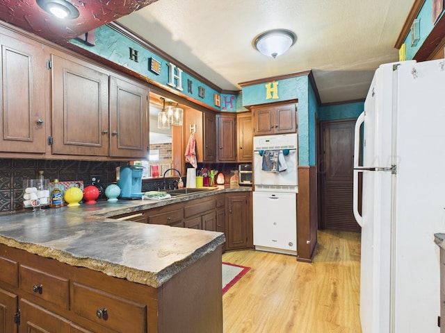 kitchen with white appliances, decorative backsplash, a sink, light wood finished floors, and a peninsula