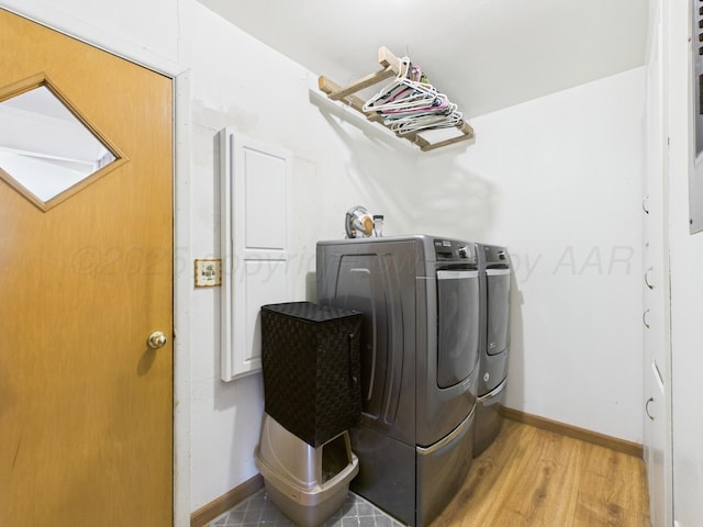 washroom featuring washing machine and clothes dryer, baseboards, laundry area, and wood finished floors