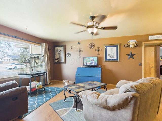 living room featuring baseboards, wood finished floors, and ceiling fan