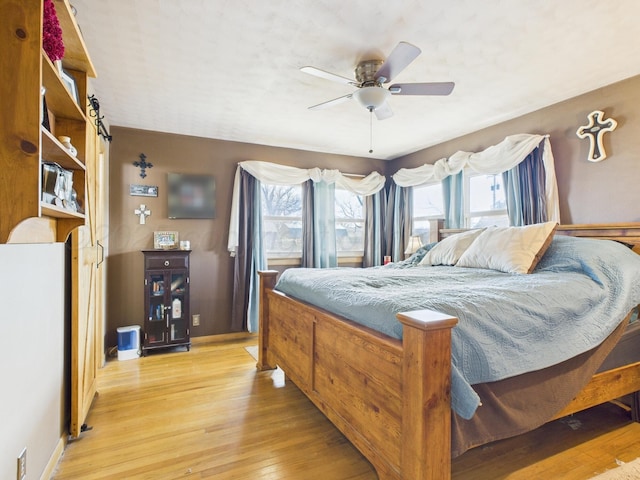 bedroom featuring light wood finished floors, multiple windows, and baseboards