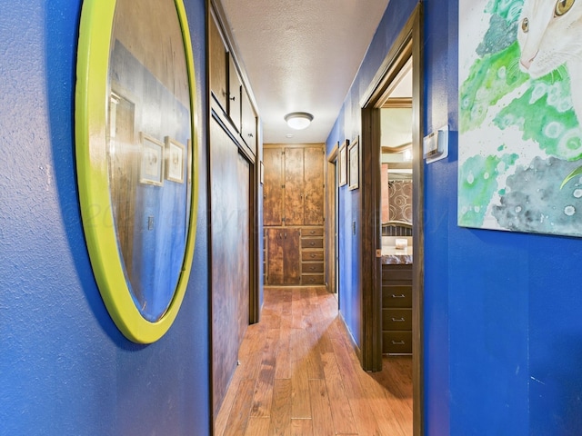 hallway with a textured ceiling and wood finished floors
