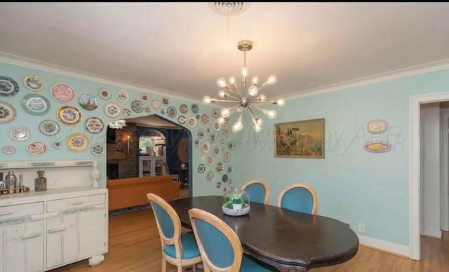 2404 S Harrison St, Amarillo, TX 79109 - dining area with crown molding, light wood finished floors, arched walkways, a chandelier, and baseboards