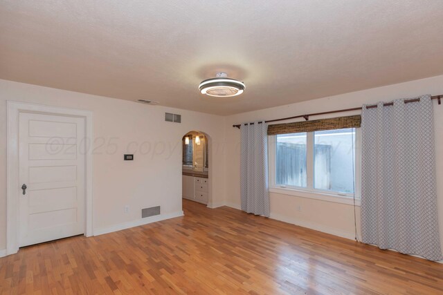 1218 N Charles St, Pampa, TX 79065 - spare room featuring arched walkways and light wood-type flooring