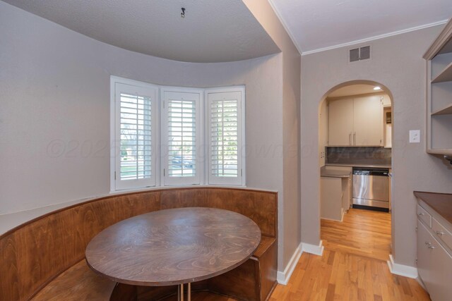 1218 N Charles St, Pampa, TX 79065 - dining area featuring light wood-type flooring, arched walkways, and crown molding
