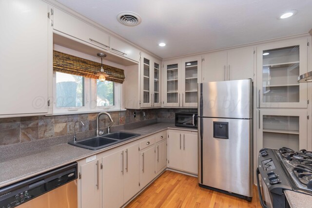 1218 N Charles St, Pampa, TX 79065 - kitchen with black appliances, light wood-style floors, decorative backsplash, glass insert cabinets, and recessed lighting