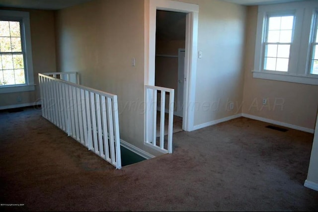 empty room featuring carpet floors, baseboards, and visible vents
