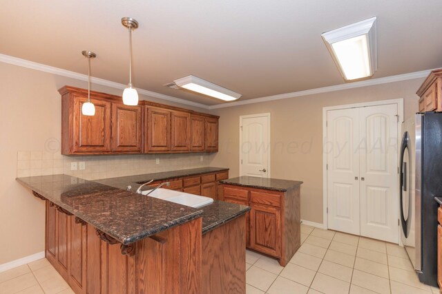 6701 Mosley St, Amarillo, TX 79119 - kitchen featuring a sink, freestanding refrigerator, brown cabinets, a center island, and a peninsula