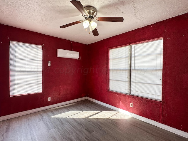 unfurnished room featuring a textured ceiling, hardwood / wood-style floors, a wall unit AC, and ceiling fan