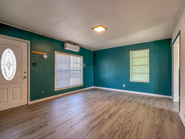 entrance foyer featuring hardwood / wood-style floors, a wall unit AC, and a textured ceiling