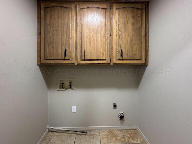 clothes washing area with hookup for an electric dryer, hookup for a washing machine, light tile patterned floors, and cabinets