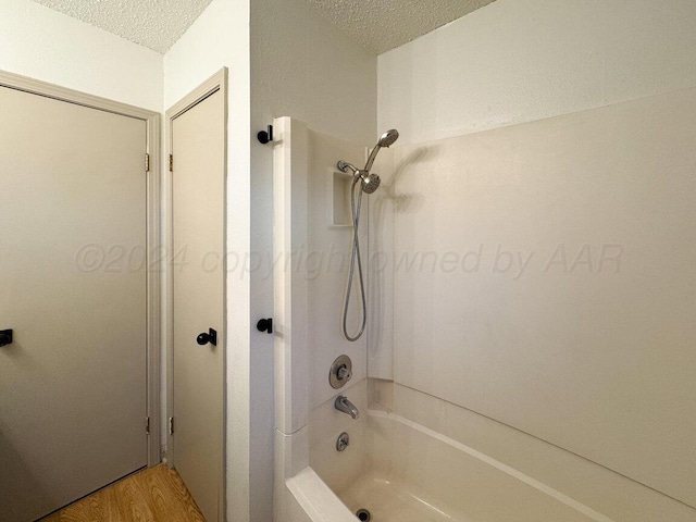 bathroom with hardwood / wood-style floors, a textured ceiling, and washtub / shower combination