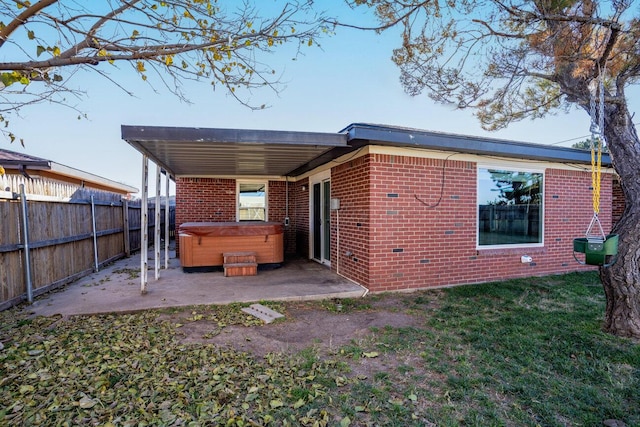 rear view of property featuring a patio area and a hot tub