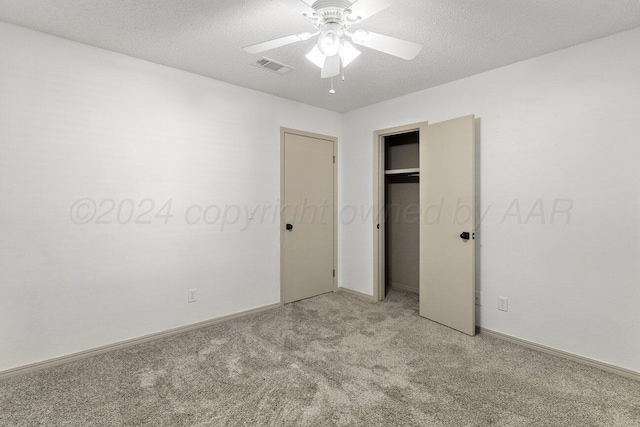 unfurnished bedroom featuring a closet, a textured ceiling, light colored carpet, and ceiling fan