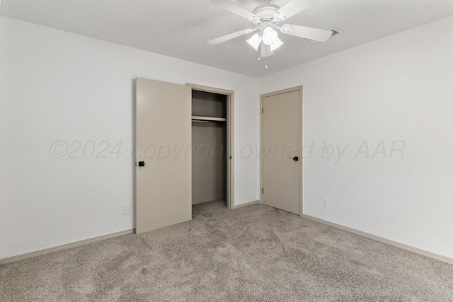 unfurnished bedroom with ceiling fan, a closet, light colored carpet, and a textured ceiling