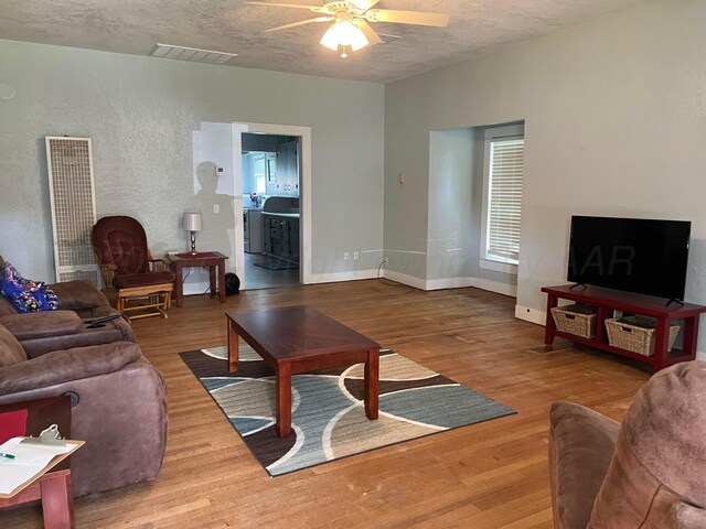 602 S Young St, Follett, TX 79034 - living area with a ceiling fan, a heating unit, wood finished floors, a textured ceiling, and baseboards