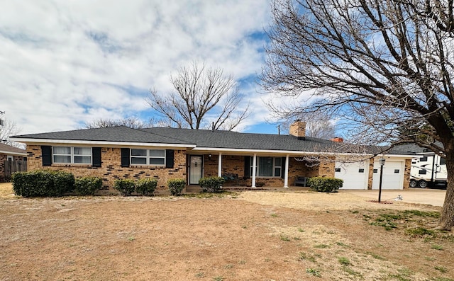 ranch-style house with a chimney, a garage, concrete driveway, brick siding, and covered porch