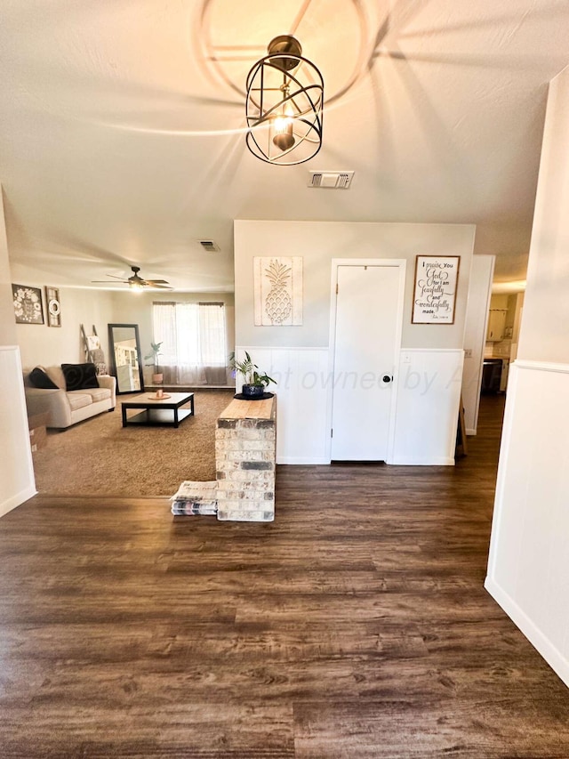 unfurnished living room with a ceiling fan, visible vents, and wood finished floors
