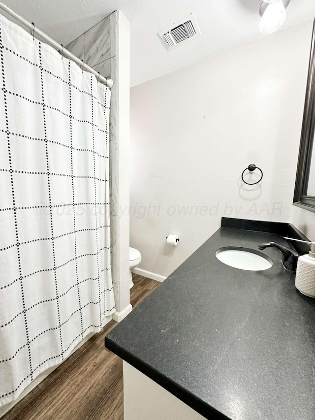 full bathroom with toilet, vanity, wood finished floors, and visible vents