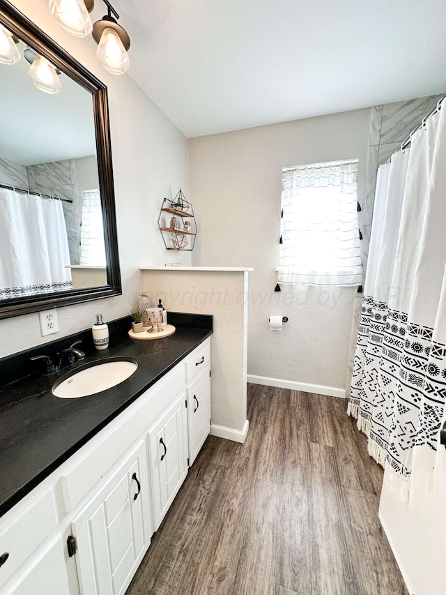 bathroom with vanity, curtained shower, baseboards, and wood finished floors