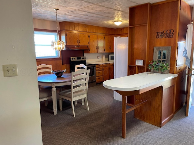 kitchen with a chandelier, under cabinet range hood, light countertops, stainless steel appliances, and brown cabinets