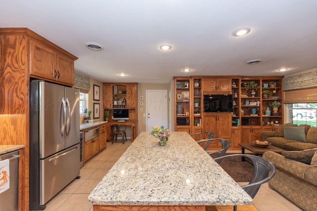 2314 Atkinsen St, Amarillo, TX 79106 - kitchen with stainless steel appliances, light tile patterned floors, open floor plan, brown cabinetry, and recessed lighting
