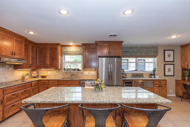 2314 Atkinsen St, Amarillo, TX 79106 - kitchen with appliances with stainless steel finishes, under cabinet range hood, a kitchen breakfast bar, light tile patterned floors, and tasteful backsplash