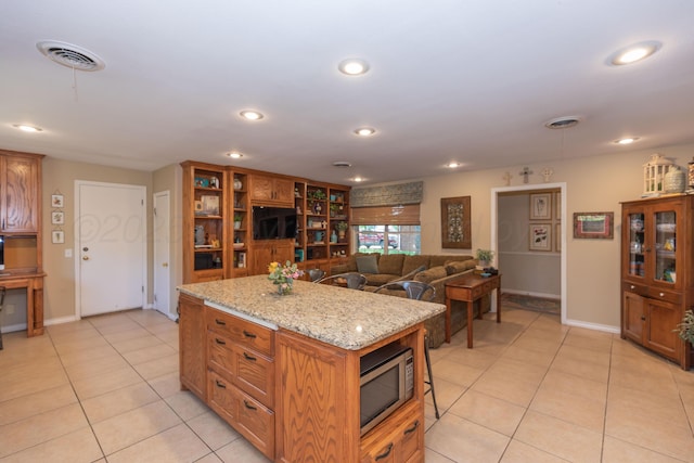 2314 Atkinsen St, Amarillo, TX 79106 - kitchen featuring stainless steel microwave, light tile patterned floors, a kitchen island, recessed lighting, and a breakfast bar area