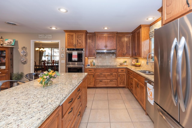 2314 Atkinsen St, Amarillo, TX 79106 - kitchen with appliances with stainless steel finishes, a chandelier, decorative backsplash, light tile patterned floors, and light stone counters