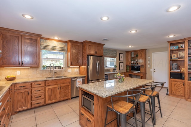 2314 Atkinsen St, Amarillo, TX 79106 - kitchen featuring appliances with stainless steel finishes, light tile patterned floors, a kitchen bar, backsplash, and brown cabinets