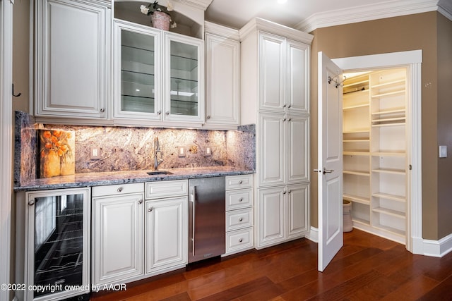 bar with stone counters, sink, fridge, dark hardwood / wood-style flooring, and beverage cooler