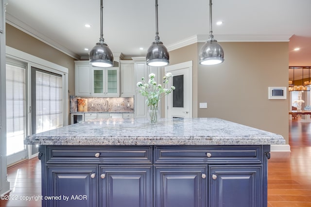 kitchen with backsplash, a center island, hanging light fixtures, and dark wood-type flooring