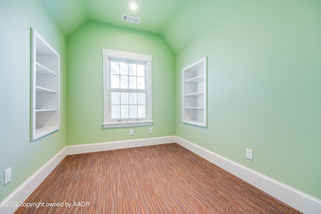 unfurnished room with built in shelves and vaulted ceiling