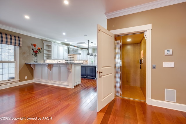 kitchen with a breakfast bar, white cabinetry, kitchen peninsula, and crown molding