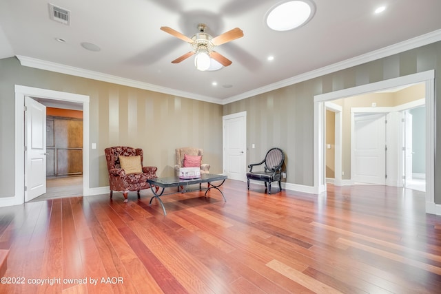 sitting room with hardwood / wood-style flooring, ceiling fan, and crown molding