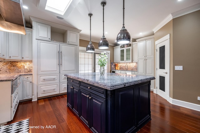 kitchen featuring a kitchen island, light stone counters, white cabinetry, and backsplash