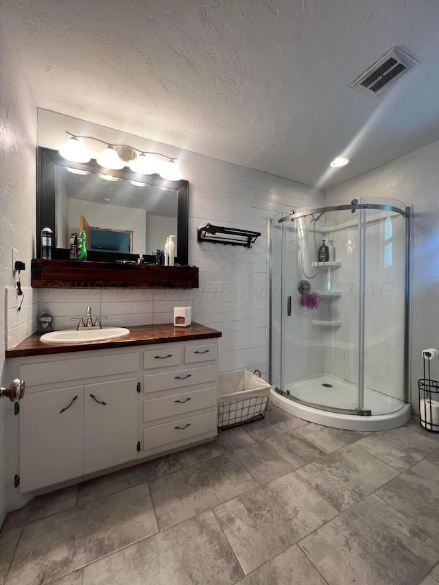 bathroom featuring vanity, an enclosed shower, and a textured ceiling