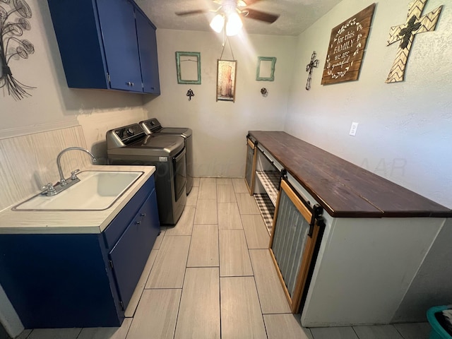 laundry area featuring ceiling fan, cabinets, sink, and washing machine and clothes dryer