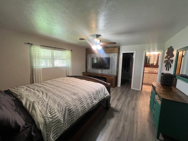 bedroom featuring a spacious closet, hardwood / wood-style floors, a closet, and a textured ceiling